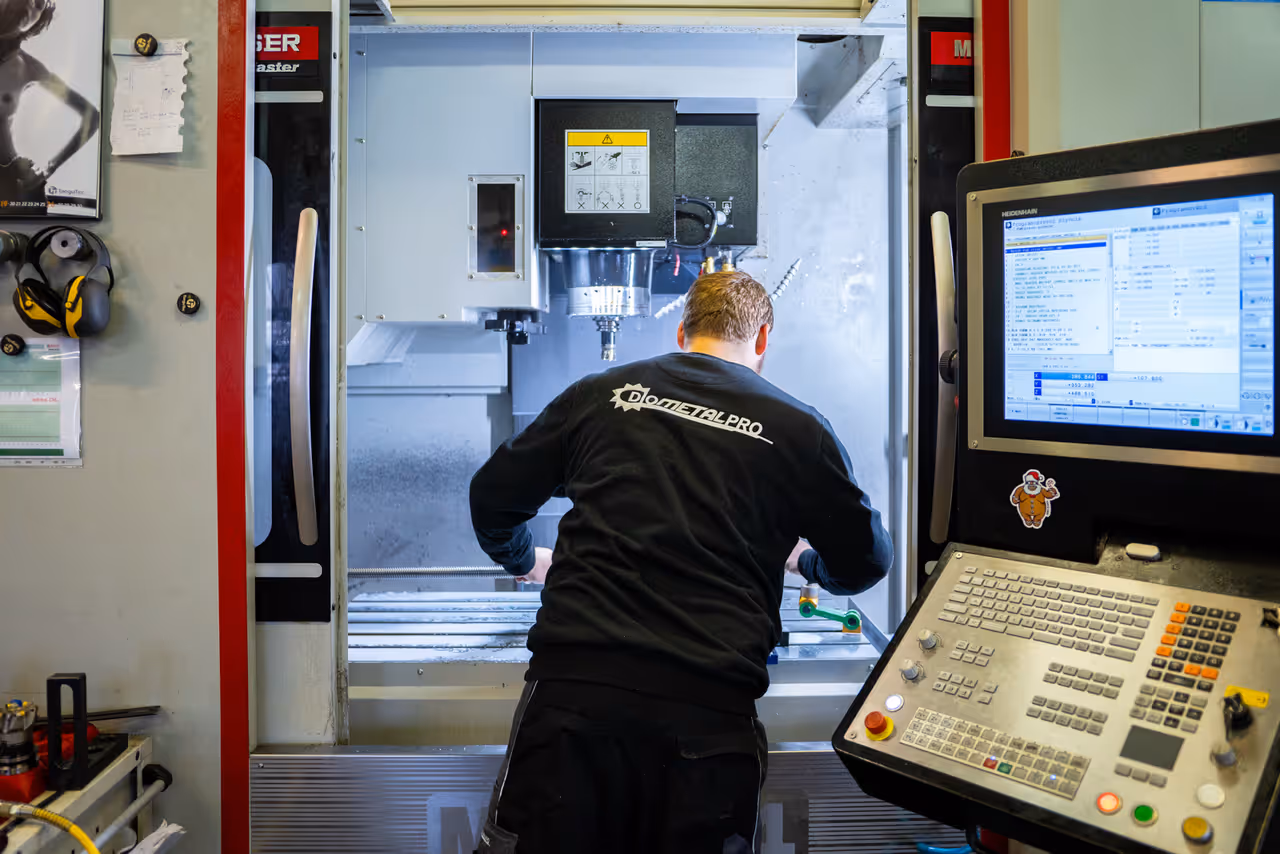 Pracovník s logem DIOMETAL PRO na zádech obsluhuje CNC obráběcí centrum